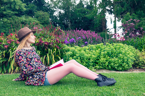 Young girl reading book in beautiful garden