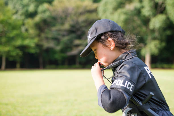 Little girl blowing whistles wearing police costumes Little girl blowing whistles wearing police costumes manhunt law enforcement stock pictures, royalty-free photos & images