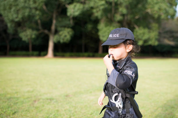 Little girl blowing whistles wearing police costumes Little girl blowing whistles wearing police costumes manhunt law enforcement stock pictures, royalty-free photos & images