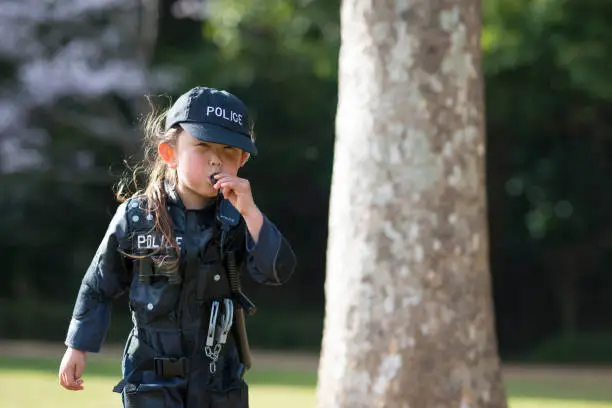 Photo of Little girl blowing whistles wearing police costumes