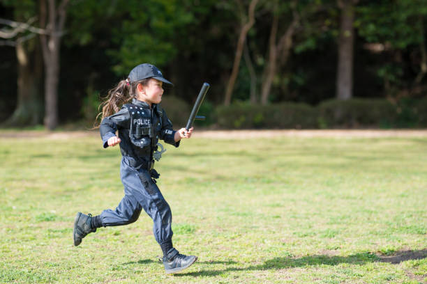 Little girl is running in police costume Little girl is running in police costume manhunt law enforcement stock pictures, royalty-free photos & images