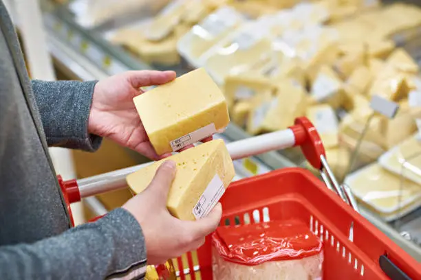 Hands of the buyer with a pieces of cheese in the store