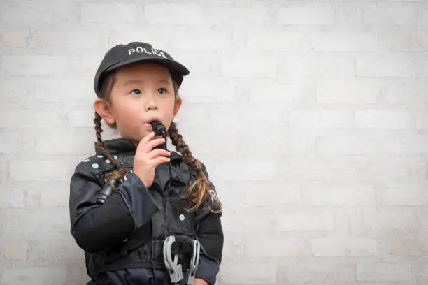 Little girl blowing whistles wearing police costumes