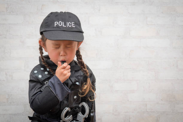 Little girl blowing whistles wearing police costumes Little girl blowing whistles wearing police costumes manhunt law enforcement stock pictures, royalty-free photos & images