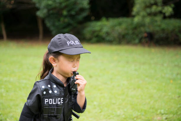 Little girl blowing whistles wearing police costumes Little girl blowing whistles wearing police costumes manhunt law enforcement stock pictures, royalty-free photos & images