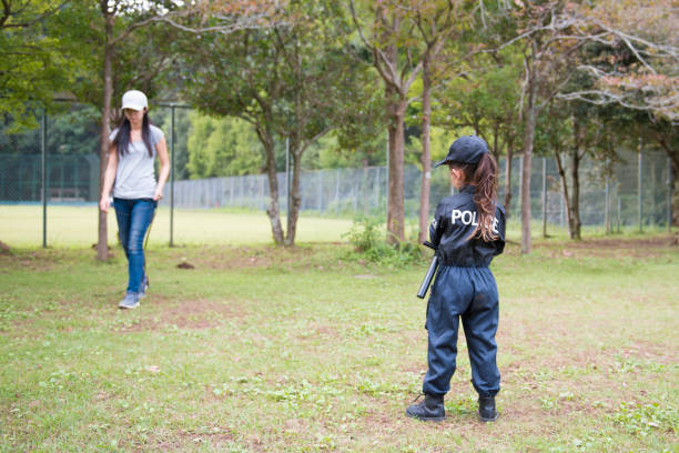 Little girl in police costume plays with mother Little girl in police costume plays with mother manhunt law enforcement stock pictures, royalty-free photos & images