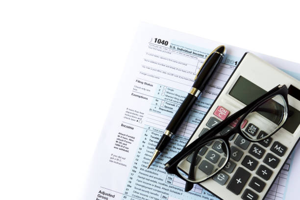 U.S Tax Filing Top view of calculator, pen, eyeglasses and out of focus U.S IRS 1040 form 1040 tax form photos stock pictures, royalty-free photos & images