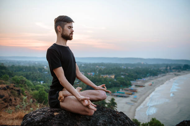 istock Healthy man practicing yoga under the beach at sunset. 942421112