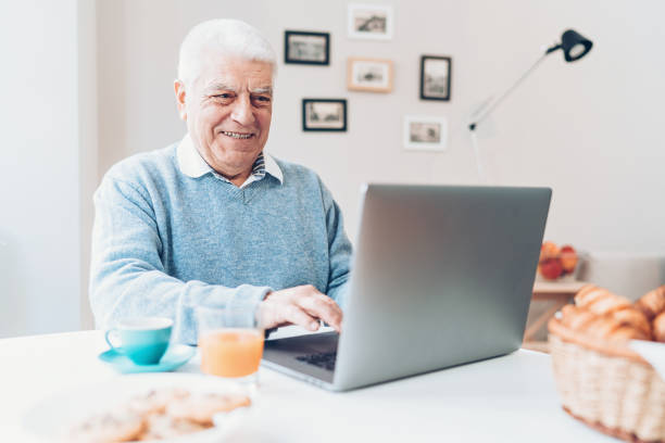 istock Smiling senior man working on a laptop at home 942425408