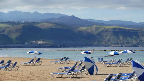 La Cantera - Beach in Las Palmas - Gran Canaria - Spain, sandy beach with chairs and umbrellas - mountains in the background