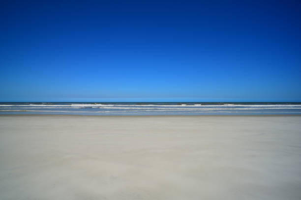 istock Facing the sea from pristine beach with single set of footprints near waters edge 942433568