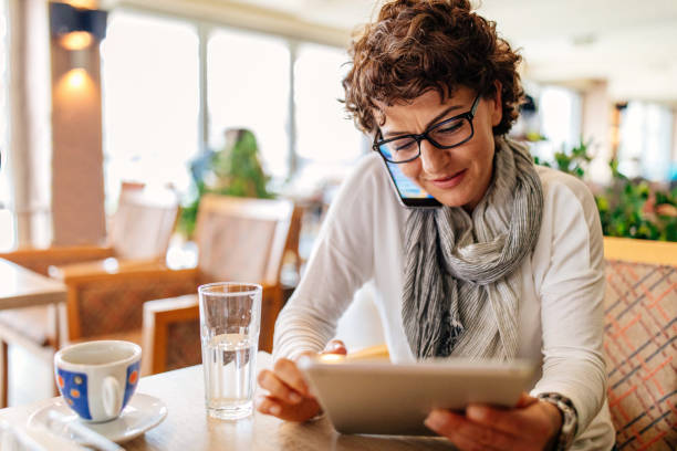istock Woman using smart phone and digital tablet at a restaurant 942443140