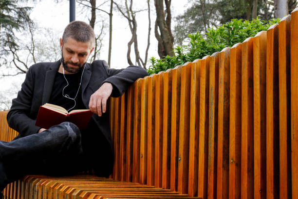 Young stylish man reading a book outdoors.