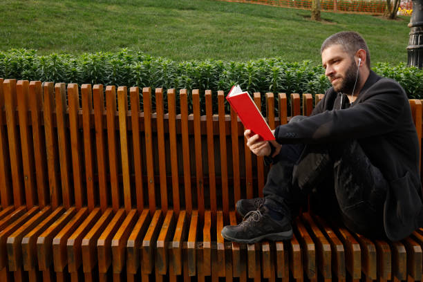 Young stylish man reading a book outdoors.
