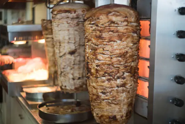 Close up shot of stacked meat roasting to be used in preparation of traditional Greek dish gyros or Turkish durum doner.