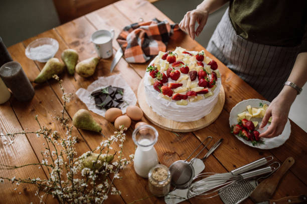 istock Woman Decorating Cake With Lemon, Lime And Strawberries 942451966