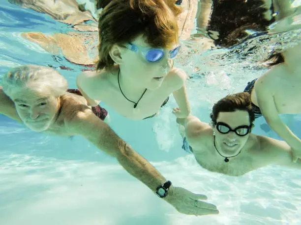 Father and Grandfather swim in children underwater on beautiful sunny summer day