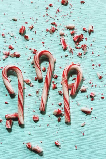 istock Xmas Candy cane and broken crushed pieces on greenish background with copy space 942459006