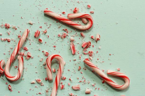 istock Xmas Candy cane and broken crushed pieces on greenish background with copy space 942459080
