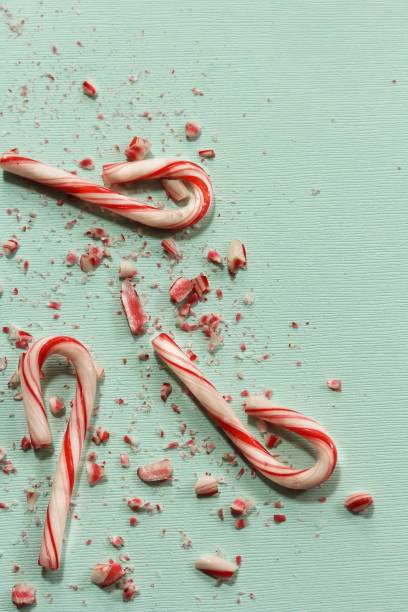 istock Xmas Candy cane and broken crushed pieces on greenish background with copy space 942459480
