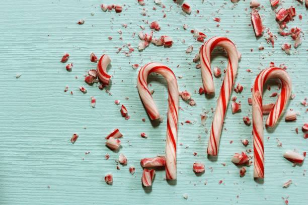 istock Xmas Candy cane and broken crushed pieces on greenish background with copy space 942459946