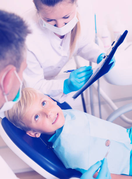 istock Dentist guy with woman assistant are diagnosticating to young patient which is sitting 942463286