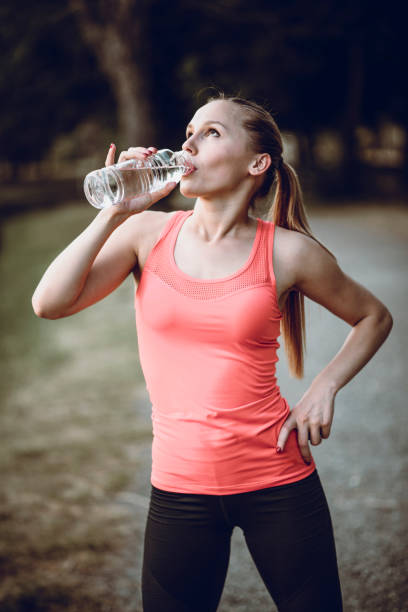 istock Young Female Resting and Drinking Water after Pilates Training in Park 942473112
