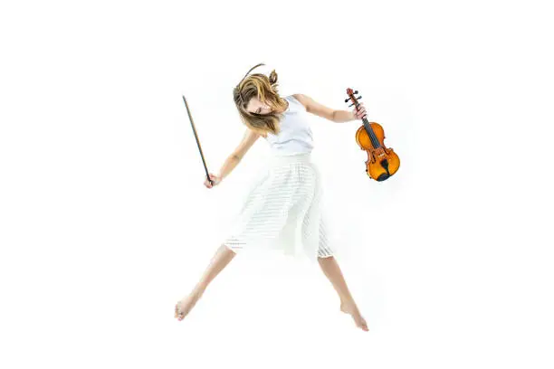 Photo of Child girl with violin jumps and flies beautiful and happy in white background
