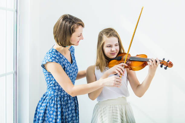 dziecko dziewczyna gra na skrzypcach jest zaangażowany z nauczycielem piękne i szczęśliwe w białym pokoju z oknem - violin musical theater musical instrument equipment zdjęcia i obrazy z banku zdjęć