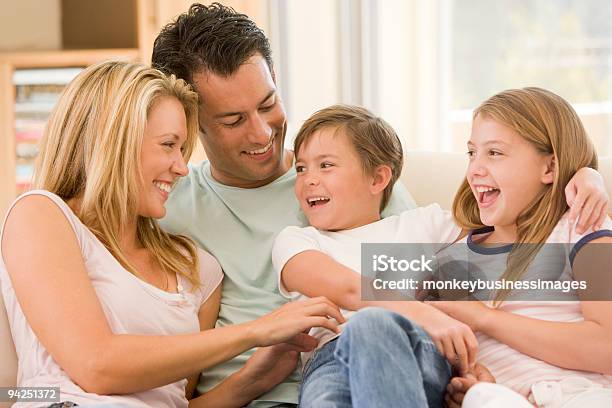 Family Sitting In Living Room Smiling Stock Photo - Download Image Now - 30-39 Years, Adult, Affectionate