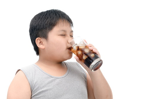 Overweight boy drinking cola isolated on white background, junk food concept