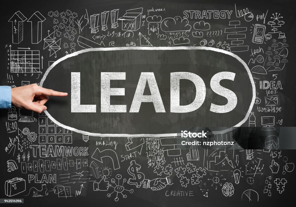 Casual businessman showing at chalk text "LEADS" with charts and diagrams on blackboard (Click for more) Lead Stock Photo