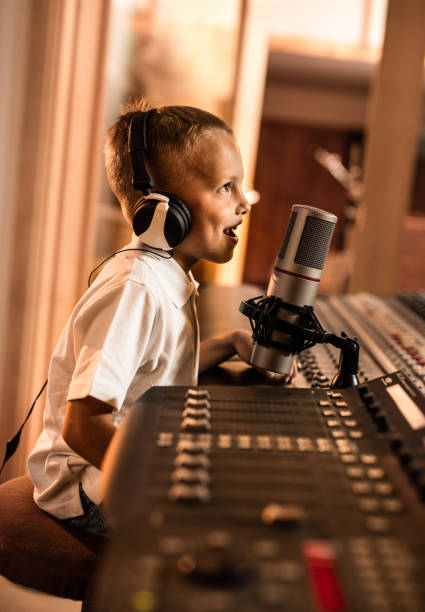 istock Happy little boy talking on a microphone in a radio station. 942514580
