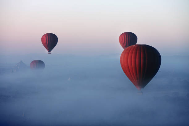 boules rouges dans la matinée dans le brouillard au-dessus de bagan. bagan est une ville située dans la région de mandalay du myanmar - blowing a balloon photos et images de collection