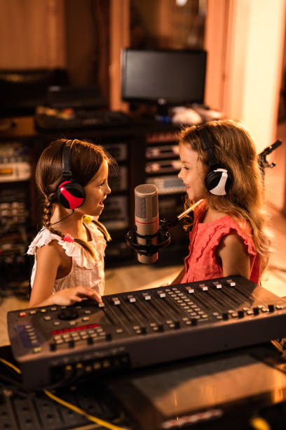 istock Two small girls having fun in a radio station while talking on a microphone. 942516088