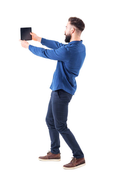elegante joven barbudo selfie foto con tableta o teléfono móvil grande. vista lateral - vista posterior fotos fotografías e imágenes de stock