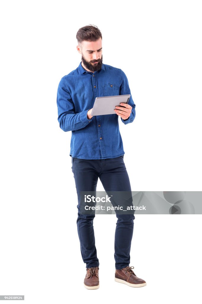 Confident serious bearded business man using tablet touch pad screen Confident serious bearded business man using tablet touch pad screen. Full body isolated on white background. Digital Tablet Stock Photo