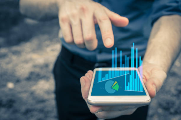 istock Hand pointing at mobile device for business use and charting data with bar charts and pie chart and valueable information on the company financial network. 942522500