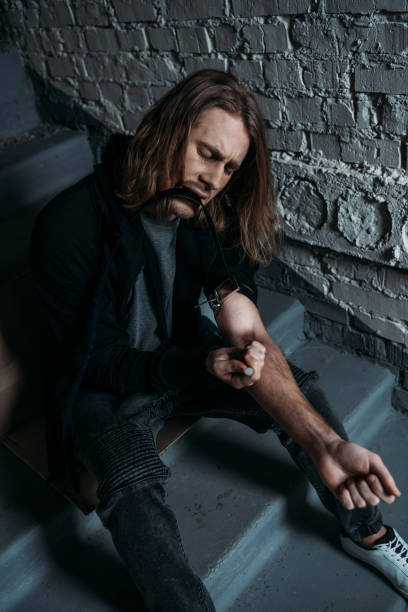 istock addicted junkie doing heroin injection on stairs 942525610
