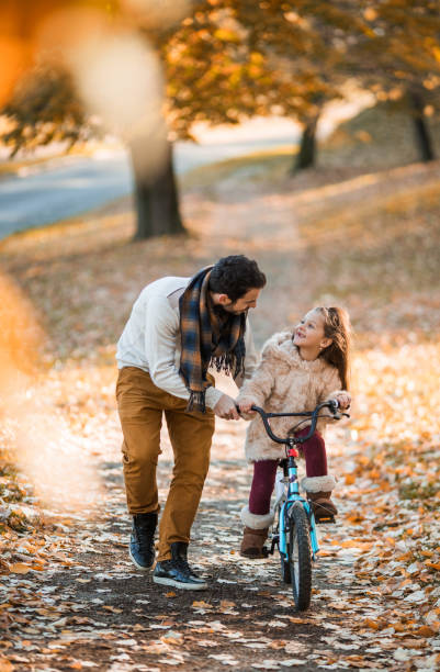 istock Young father assisting his daughter in riding a bicycle. 942527828