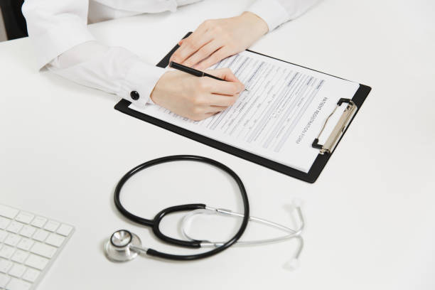 Doctor hands working filling out medical documents in light office in hospital. Woman writing on paper in clipboard, stethoscope on table in consulting room. Medicine concept. Top view. Copy space. Doctor hands working filling out medical documents in light office in hospital. Woman writing on paper in clipboard, stethoscope on table in consulting room. Medicine concept. Top view. Copy space niñas stock pictures, royalty-free photos & images