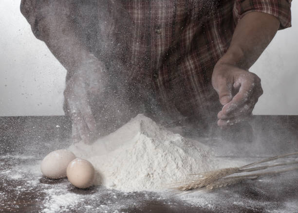 istock Man preparing bread dough on wooden table in a bakery close up 942540934