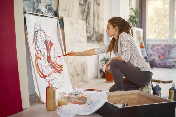 istock Artistic girl sitting in studio and paint on easel. 942546336