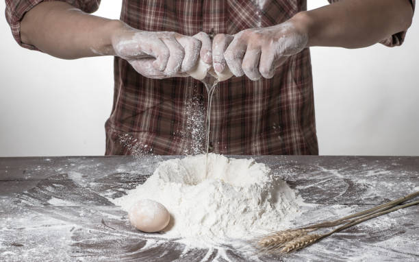 istock Man preparing bread dough on wooden table in a bakery close up 942546368