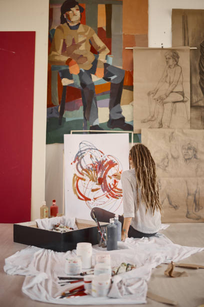istock Artistic girl sitting in studio and paint on easel. 942546498