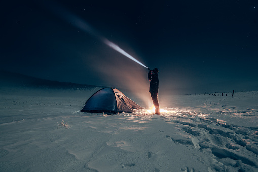 Camper standing in front of his tent with a battery lamp