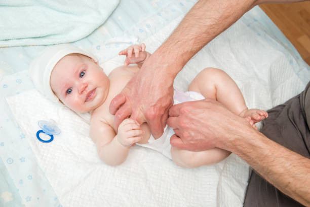 istock Dad puts a diaper on the baby. 942552728