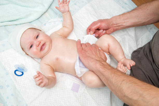 istock Dad puts a diaper on the baby. 942552744