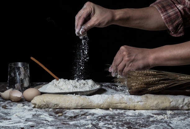 istock Man preparing bread dough on wooden table in a bakery close up 942556018