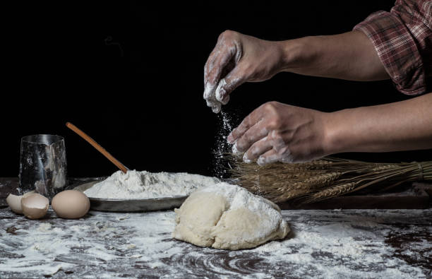 istock Man preparing bread dough on wooden table in a bakery close up 942558888